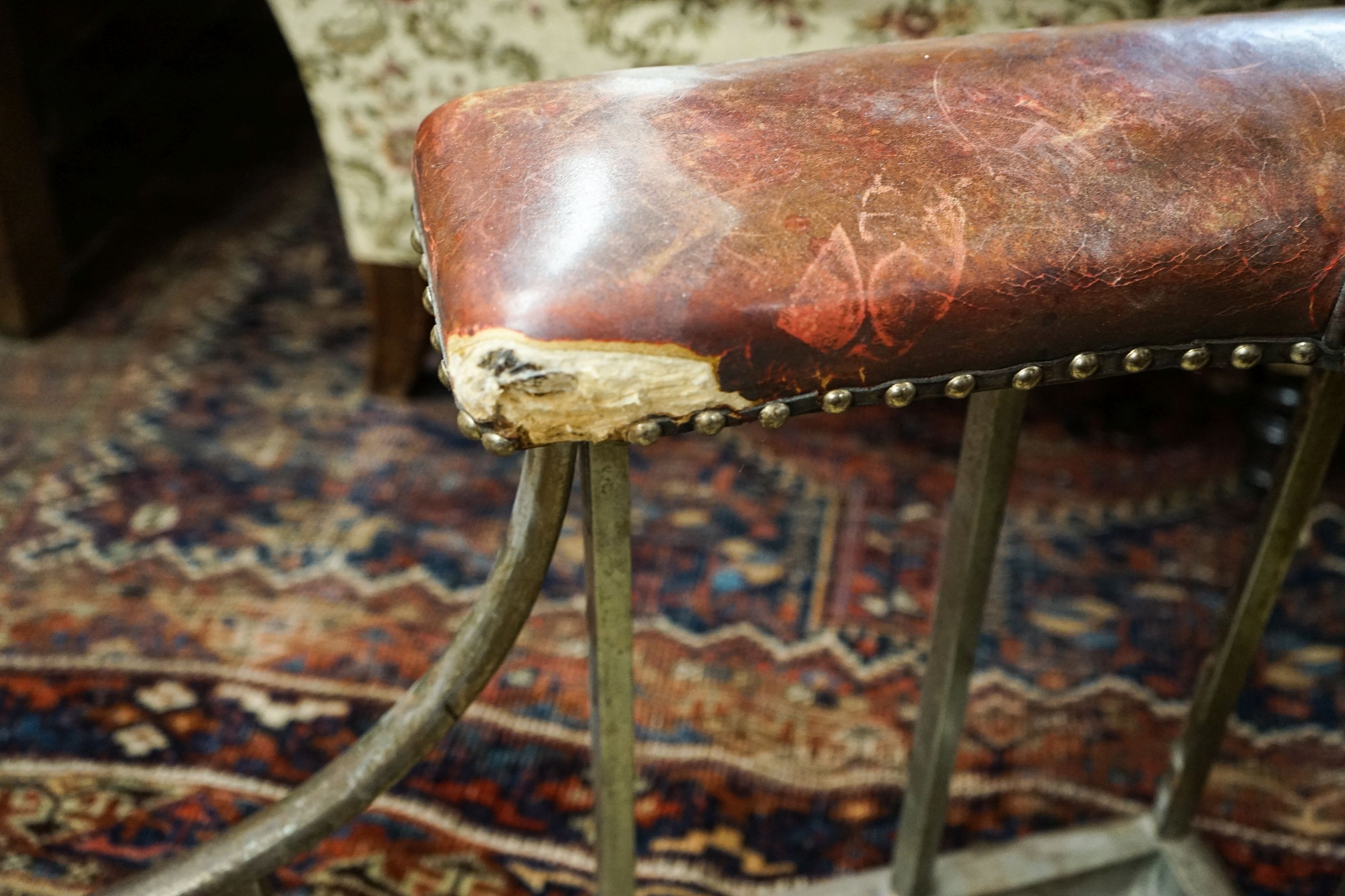 An early 20th century steel and burgundy leather club fender, length 140cm, depth 58cm, height 50cm